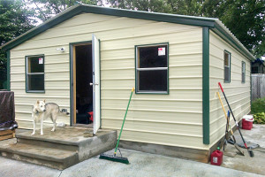 Steel building garage with many windows and a dog standing on the porch.