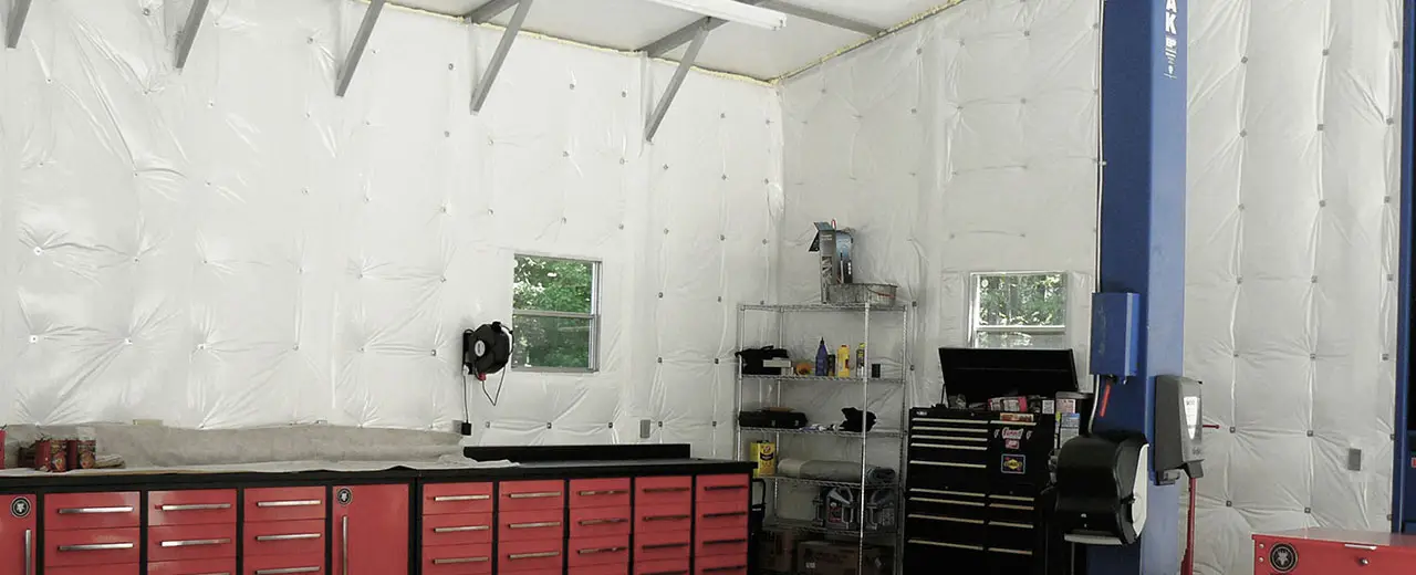 Insulated metal building garage inter with workshop bench, tools and automotive lift.