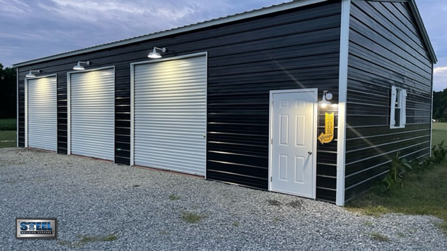 30x51 Storage Building by Steel Building Garages, exterior with custom lighting over garage doors and access door entrance.